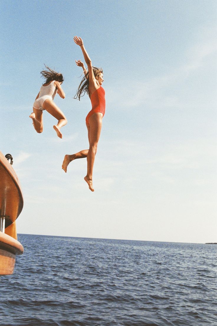 Two friends jumping off a boat, mid-adventure